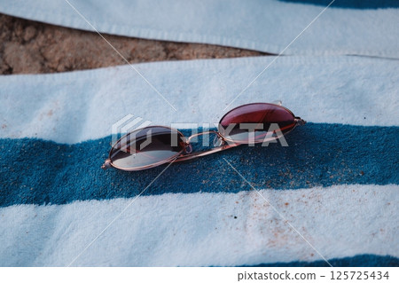 Stylish Sunglasses Placed on a Beach Towel for the Perfect Summer Vibes and Relaxation Stylish Sunglasses Placed on a Beach Towel for the Perfect Summer Vibes and Relaxation 125725434