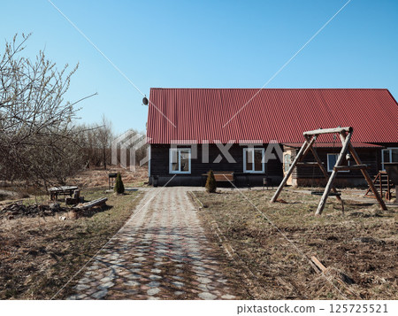Charming Countryside Home Featuring a Vibrant Red Roof and a Fun Swing Set for Kids Charming Countryside Home Featuring a Vibrant Red Roof and a Fun Swing Set for Kids 125725521