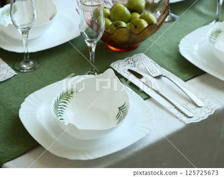 An Elegant Dining Table Setting Enhanced with Green Accents and Vibrant Fresh Fruits An Elegant Dining Table Setting Enhanced with Green Accents and Vibrant Fresh Fruits 125725673