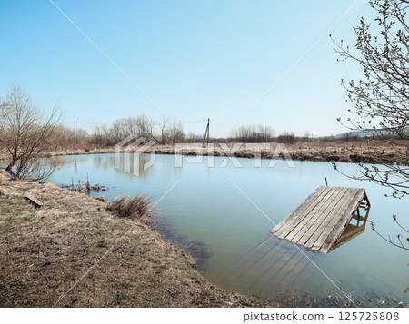 A Serene Pond Accompanied by An Abandoned Dock Nestled Within A Tranquil Natural Landscape 125725808