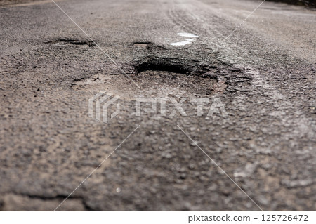 A significant crack in the asphalt on a highway poses a danger for drivers, necessitating immediate maintenance and repair efforts 125726472