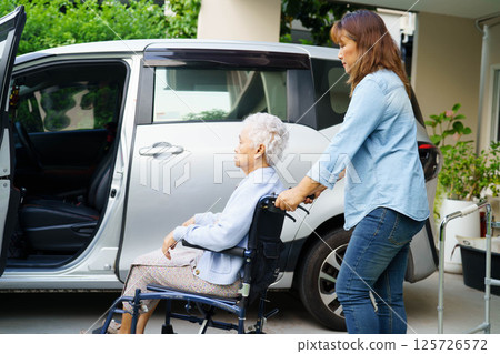Caregiver help Asian elderly woman disability patient use wheelchair to get in car. Caregiver help Asian elderly woman disability patient use wheelchair to get in car. 125726572