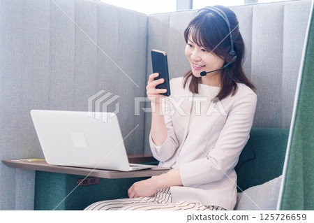 A young business person skips a remote meeting and uses a smartphone A young business person skips a remote meeting and uses a smartphone 125726659