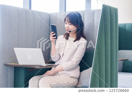 A young business person skips a remote meeting and uses a smartphone A young business person skips a remote meeting and uses a smartphone 125726660