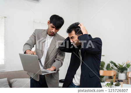 Business Dynamics and Team Interaction. Two colleagues engaged in a heated discussion over project details in a contemporary office. Business Dynamics and Team Interaction. Two colleagues engaged in a heated discussion over project details in a contemporary office. 125726807