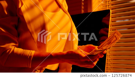 Female Entrepreneur Holding Cash near Window Blinds. 125726874