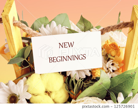A beautiful arrangement of colorful flowers, including daisies and roses, surrounded by greenery and featuring a sign that reads New Beginnings in a warm, inviting atmosphere 125726901