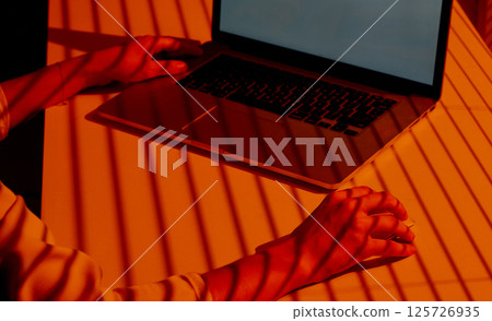 Woman Using Laptop and Mouse in Sunset Shadow Light. 125726935