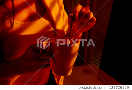 Closeup of Woman Stirring Mug in Cozy Office Lighting. 125726939