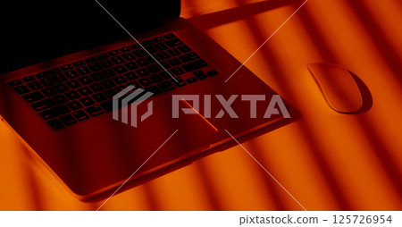 Modern Laptop and Mouse in Dramatic Orange Light. Modern Laptop and Mouse in Dramatic Orange Light. 125726954