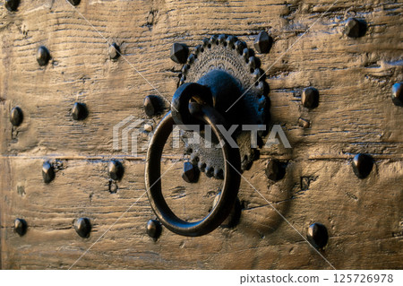 Rustic metal door knocker on vintage wooden surface with textured design Rustic metal door knocker on vintage wooden surface with textured design 125726978