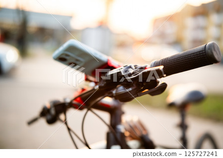 Smartphone On Bicycle Handlebar On City Street Smartphone On Bicycle Handlebar On City Street 125727241