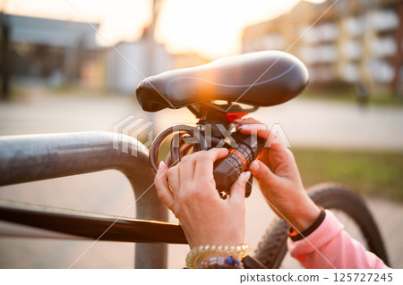 Girl Sets Code On A Code Bike Lock And Secures Bicycle At Bike Rack Girl Sets Code On A Code Bike Lock And Secures Bicycle At Bike Rack 125727245