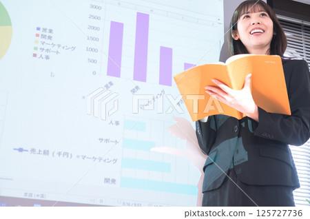 一位身穿西裝的年輕女子在投影機前做演示 125727736