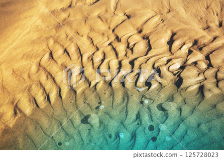 Abstract sandy beach background. The sand texture on the beach at low tide Abstract sandy beach background. The sand texture on the beach at low tide 125728023