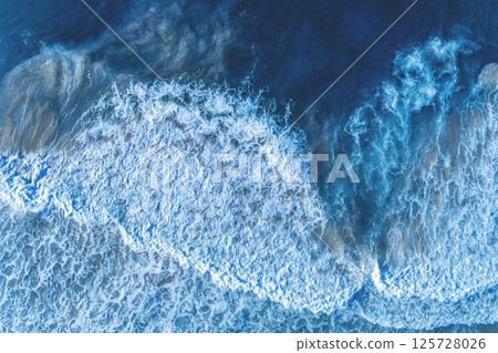 Ocean surf. Waves roll onto the shore. View from above. Natural abstract background 125728026