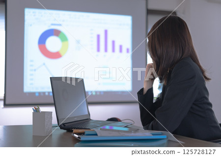 A woman in a suit struggling to create presentation materials 125728127