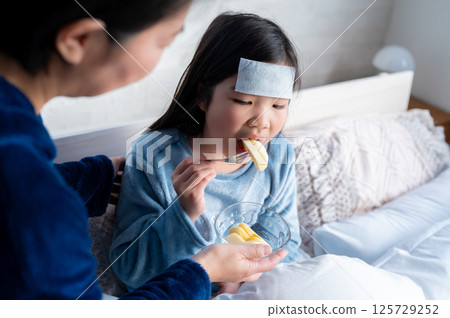 A girl eating a meal while cooling her forehead with an ice pack and cooling sheet A girl eating a meal while cooling her forehead with an ice pack and cooling sheet 125729252