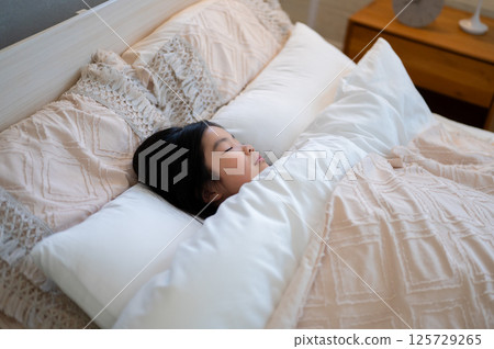 The sight of a sleeping child with his eyes closed, wrapped in a futon, brings a sense of calm and comfort. 125729265