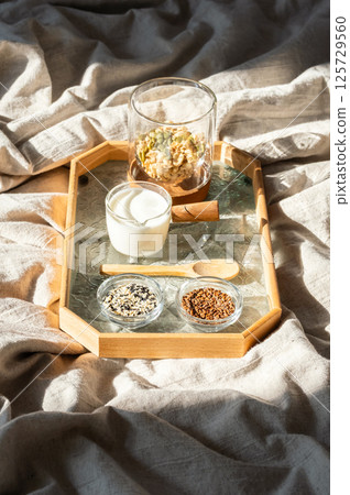 Healthy Morning Meal with Granola and Seeds on Linen Bed. Breakfast Ingredients Concept. Healthy Morning Meal with Granola and Seeds on Linen Bed. Breakfast Ingredients Concept. 125729560