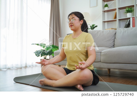 Asian women meditate and practice yoga in the living room at home, home health care, exercise 125729740