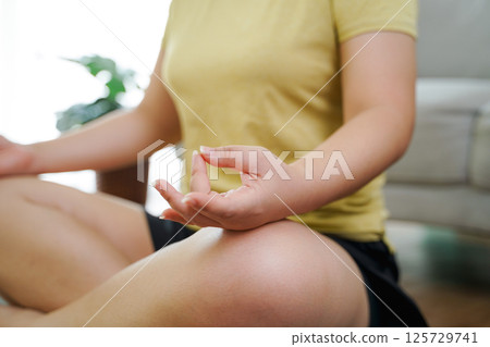 Asian women meditate and practice yoga in the living room at home, home health care, exercise Asian women meditate and practice yoga in the living room at home, home health care, exercise 125729741