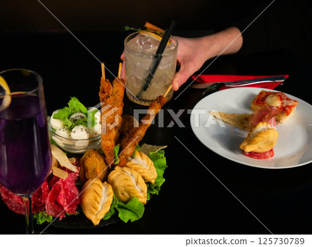 Cocktails and Appetizers on a Dark Table 125730789
