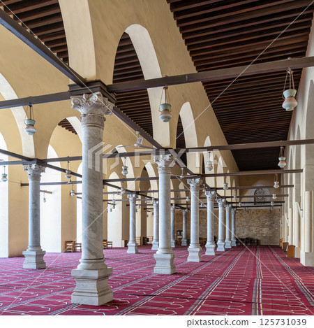 Historic mosque of al-Zahir Baybars features intricate columns and a vibrant prayer carpet in Cairo, Egypt 125731039