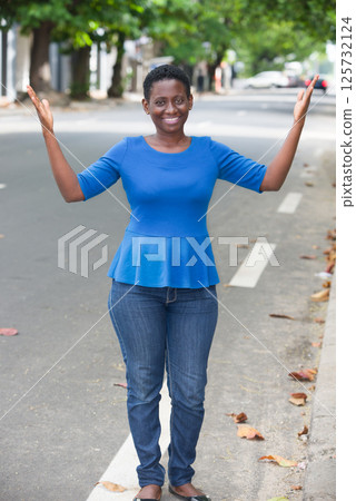 Beautiful girl holding hands on the sides outdoors. Beautiful girl holding hands on the sides outdoors. 125732124