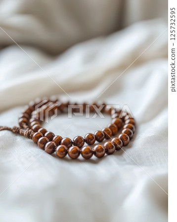 Elegant brown prayer beads on soft fabric background 125732595