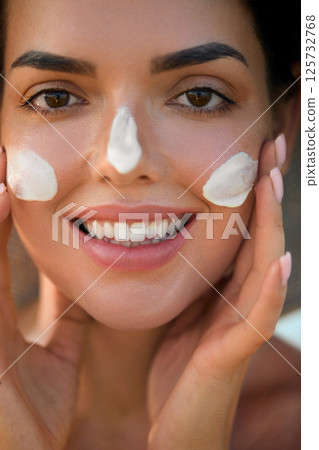 Beauty woman with moisturising cream, sunscreen product or sun tan lotion on her cheek, luxury facial and skin care. Suntan spf and skincare cosmetics model face portrait, Beauty woman with moisturising cream, sunscreen product or sun tan lotion on her cheek, luxury facial and skin care. Suntan spf and skincare cosmetics model face portrait, 125732768