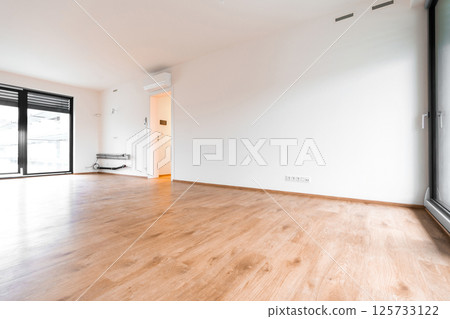 Modern bright unfurnished room with wooden flooring and tilt and turn windows in Czech apartment 125733122