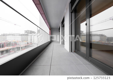 Modern city balcony with glass railing and urban construction view 125733123