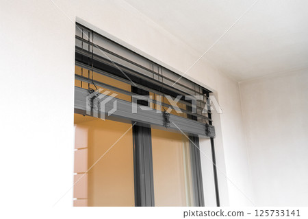 Tilt and turn window and door system with closed roller shutters in a modern apartment balcony 125733141