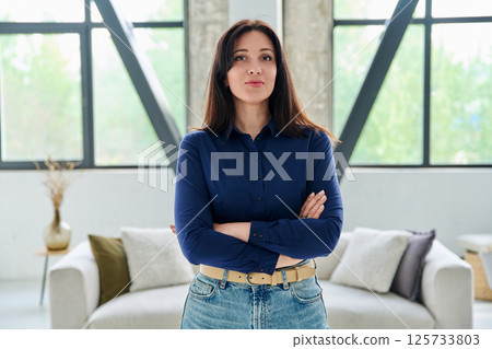 Portrait of beautiful young confident woman in office with couch Portrait of beautiful young confident woman in office with couch 125733803