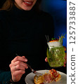 Woman Enjoying Appetizers and a Green Cocktail 125733887