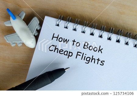 How to book a cheap flights text on white notepad with airplane and black pen background 125734106