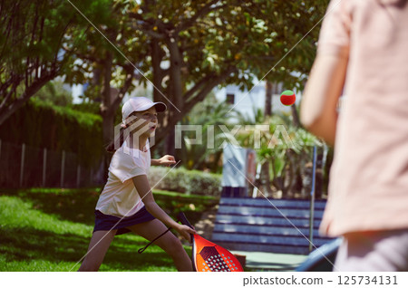 Outdoor Weekend Tennis Game Between Family Members in a Sunny Park Outdoor Weekend Tennis Game Between Family Members in a Sunny Park 125734131