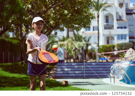Young Girl Enjoying Padel Tennis at an Outdoor Park with Scenic Views Young Girl Enjoying Padel Tennis at an Outdoor Park with Scenic Views 125734132