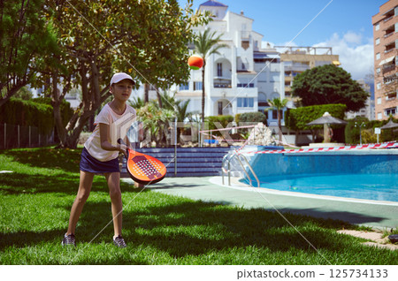 Child Playing Paddle Tennis Near Poolside on a Sunny Day Child Playing Paddle Tennis Near Poolside on a Sunny Day 125734133