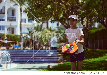 Young Girl Enjoying Paddle Tennis in a Sunny Outdoor Setting 125734134