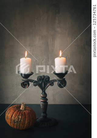 Atmospheric vintage candelabrum with burning candles and small pumpkin on the table, vertical image, copy space. Atmospheric vintage candelabrum with burning candles and small pumpkin on the table, vertical image, copy space. 125734761