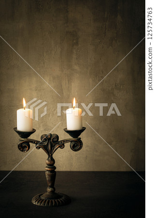 Atmospheric vintage candelabrum with burning candles on the table, vertical image, copy space. Atmospheric vintage candelabrum with burning candles on the table, vertical image, copy space. 125734763