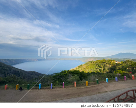 Scenic view of serene lake surrounded by hills during clear day 125734897