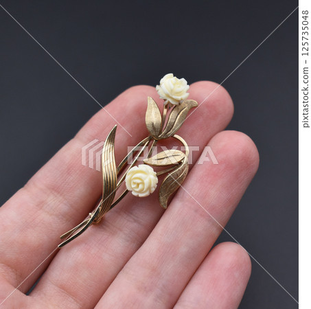 Feminine brooch with floral charm on linen surface 125735048