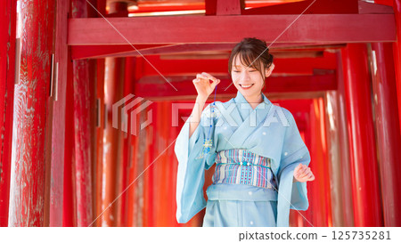 日本的夏天：一位穿著浴衣的女子站在鳥居門前，手裡拿著風鈴 125735281