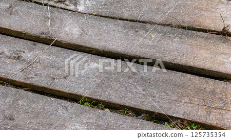 Wooden boards with grass breaking through sprinkled with snow Wooden boards with grass breaking through sprinkled with snow 125735354
