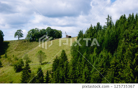 Lonely small wooden house on a hill, mountain cloudy landscape 125735367