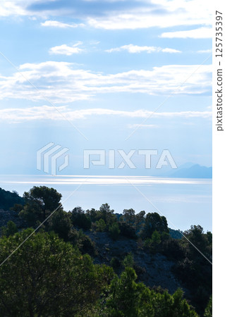 A patch of sunlight on the sea under a blue sky, view from a hill A patch of sunlight on the sea under a blue sky, view from a hill 125735397