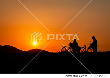 Silhouette of a woman and bicycle on a sunset background 125735585